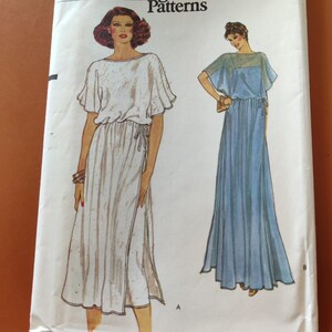 May include: A sewing pattern for a long, flowing dress with a tie at the waist. The pattern includes two different styles, one with a short sleeve and one with a long sleeve. The pattern is for sizes 6-14.