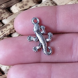 Peut inclure: Breloque en argent en forme de lézard. Le breloque est détaillé avec des écailles et a une boucle pour l'attacher à un collier ou un bracelet.