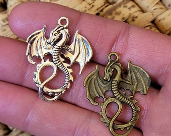 May include: Two silver dragon charms with wings outstretched. One charm is silver and the other is bronze.