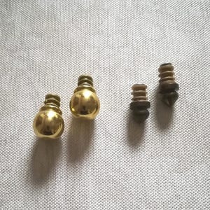 May include: Four small furniture knobs. Two are gold-coloured and bulbous, with a threaded base. The other two are smaller, with a brown and black colour scheme and a pointed end.