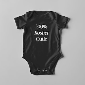 Op de afbeelding: Zwarte baby romper met witte tekst "100% Kosher Cutie".