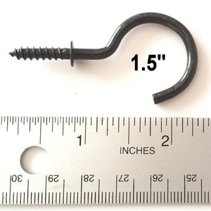 May include: A black metal screw-in hook with a 1.5 inch hook. The hook is measured against a ruler.