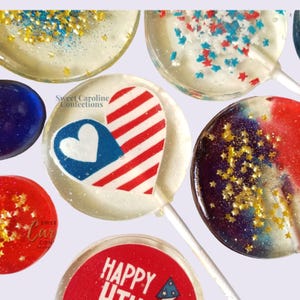 Puede incluir: Una colección de piruletas redondas de caramelo duro transparente y de colores. Una piruleta muestra un corazón con rayas rojas y blancas y una sección azul con un corazón blanco. Otra tiene el texto Happy 4th. Otras contienen chispas de estrellas doradas.