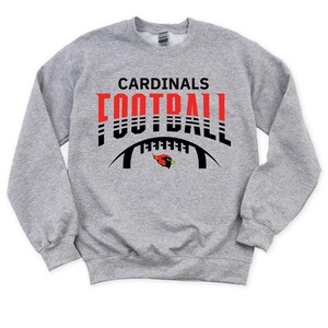 Peut inclure: Sweat-shirt gris avec un graphique noir et rouge d'un ballon de football avec le texte "CARDINALS FOOTBALL" au-dessus.
