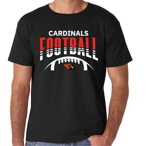 Peut inclure: T-shirt noir avec un motif graphique blanc et rouge qui dit "CARDINALS FOOTBALL" avec un oiseau cardinal rouge et une arche de football blanche.