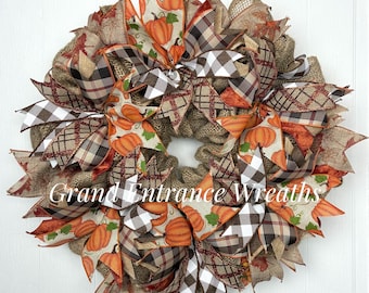 Corona rústica de arpillera para otoño: decoración de puerta con cintas y calabazas de estilo granja.