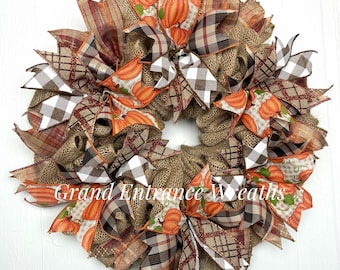 Corona rústica de arpillera para otoño: decoración de puerta con cintas y calabazas de estilo granja.