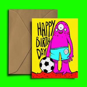 May include: A yellow birthday card with a pink monster holding a soccer ball. The monster is wearing blue shorts with a patch that says "Space United FC". The card says "Happy Birthday" in black letters.