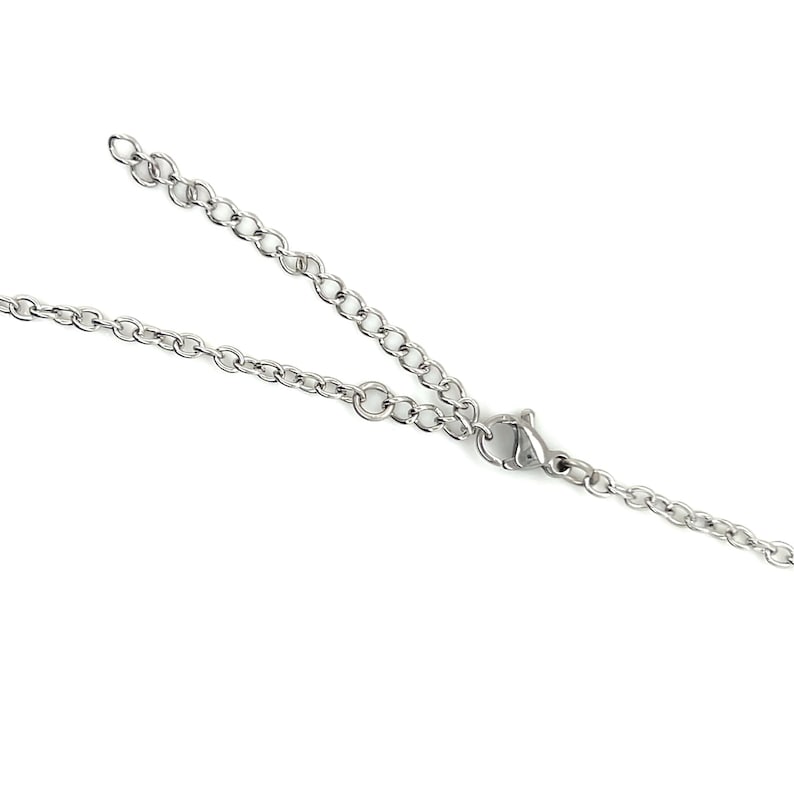 May include: A silver-colored necklace with a delicate chain and a lobster clasp. The chain is made of small, interconnected links. The necklace is displayed against a white background.