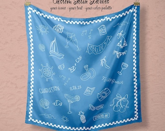 May include: A square blue satin scarf featuring a white checkered border and white line-art illustrations including a sailboat, wedding rings, a ship wheel, a camera, cherries, and text reading Custom Satin Scarves, BZ+CSF, Charleston, 11.08.25, Folly Beach, King St, and Bride.