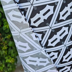 a close-up view of a fabric with a repeating pattern of black and white geometric shapes, resembling a bat pattern.