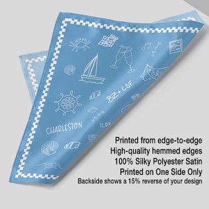 The image is a printed fabric with a design featuring various objects such as a ship, a boat, a lighthouse, and a crab. The text indicates that the fabric is printed from edge-to-edge, has high-quality hemmed edges, and is made of silk polyester satin. The fabric is printed on one side only, and the backside shows a 15% reverse of the design.