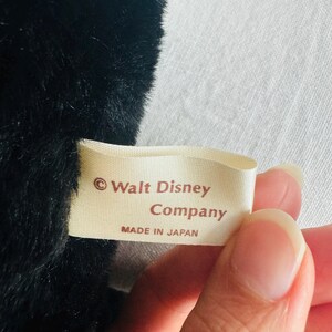 Może przedstawiać: Biała metka z brązowym tekstem, na kt&oacute;rej widnieje napis "&copy; Walt Disney Company Wyprodukowano w Japonii".
