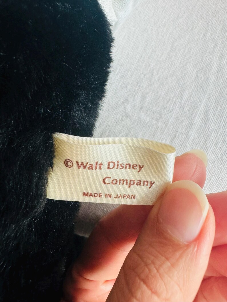Może przedstawiać: Biała metka z brązowym tekstem, na kt&oacute;rej widnieje napis "&copy; Walt Disney Company Wyprodukowano w Japonii".