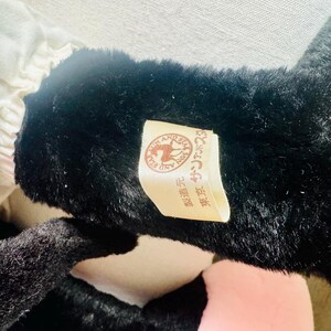 Może przedstawiać: Pluszowa zabawka w kolorze czarno-białym z brązową metką, na kt&oacute;rej widnieje napis "Pony and Bear" w języku japońskim. Metka zawiera r&oacute;wnież obrazek konia i niedźwiedzia.