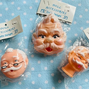 May include: Three plastic doll heads with facial features, including a white beard and mustache, glasses, and a pink mouth. The doll heads are packaged in clear plastic bags with labels that read "Doll Accessories" and "Crafts Delight".