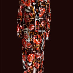 May include: A long-sleeved dress with a brown, white and orange geometric pattern featuring red poppy flowers. The dress has a collared neckline and button closure.