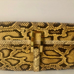 May include: A yellow and brown snakeskin clutch with a gold metal clasp.