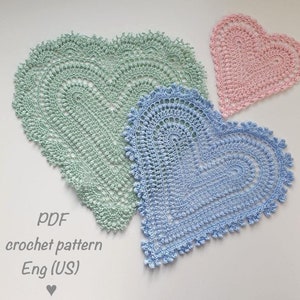 May include: Three crocheted heart-shaped doilies in different sizes. The largest doily is green, the middle doily is blue, and the smallest doily is pink. The text "PDF crochet pattern Eng (US)" is written below the doilies.