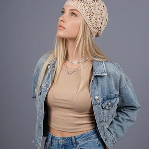 May include: A beige crocheted hat with a floral design. The hat is worn with a denim jacket and jeans. The image also includes the text "KALYNA.ART ig: the.kalyna.art".