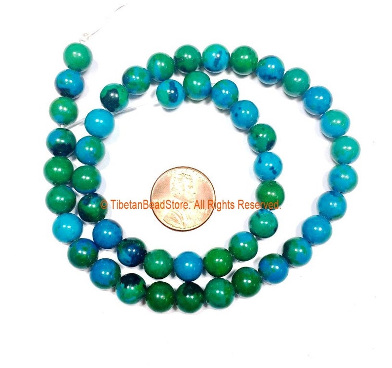 May include: A strand of green and blue gemstone beads, approximately 8mm in diameter. The beads are round and have a smooth, polished finish. The beads are strung on a clear thread and are displayed against a white background. &copy;TibetanBeadStore. All Rights Reserved.