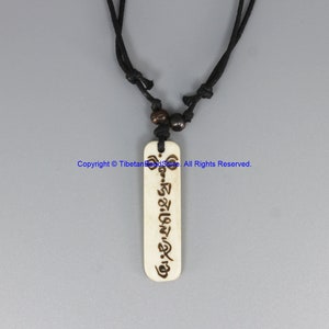May include: A white bone pendant necklace with a black cord and brown beads. The pendant has Tibetan writing engraved on it.  Copyright © TibetanBeadStore All Rights Reserved.