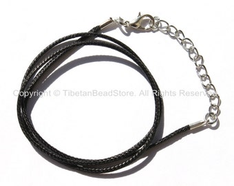 May include: Black necklace cord with a silver-colored clasp and chain extender. The cord is made of a woven material. The image is on a white background.