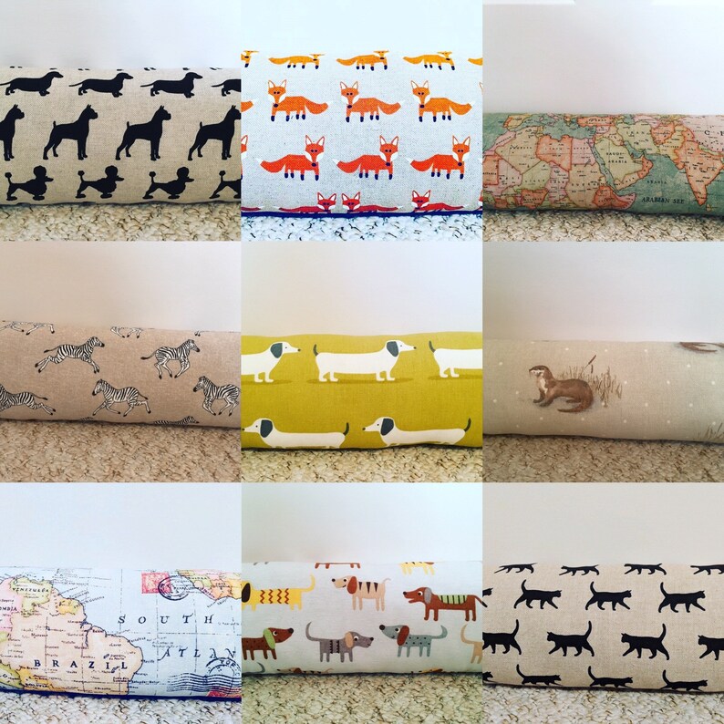 May include: A collection of decorative door draft stoppers. The stoppers feature various patterns, including black dog silhouettes, orange foxes, a world map, zebras, dachshunds, an otter, and black cat silhouettes. Each stopper is rectangular.