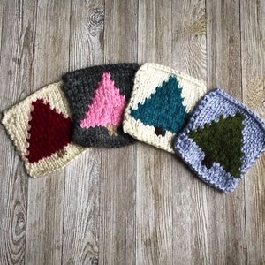 Puede incluir: Cinco cuadrados tejidos con árboles de diferentes colores en el centro. Los cuadrados son blancos con un borde gris, azul, verde, rojo y rosa.