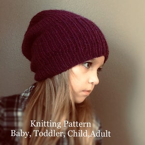 May include: A close-up of a child wearing a deep purple knitted beanie. The beanie is slouchy and has a ribbed texture. The text "Knitting Pattern Baby, Toddler, Child, Adult" is visible below the child's face.