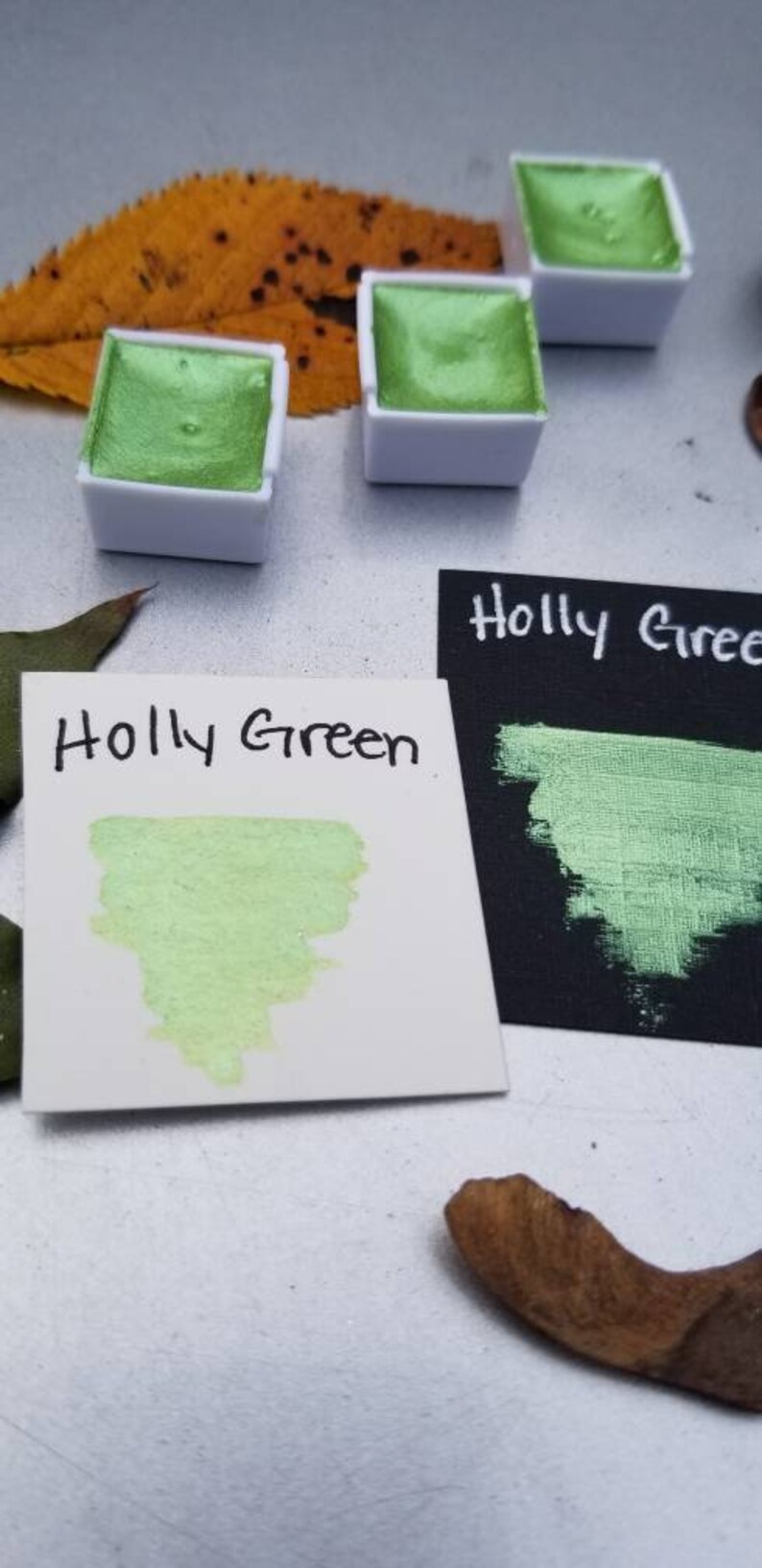 May include: Two small pans of metallic green watercolor paint, labeled "Holly Green", with a sample of the paint on a white card.