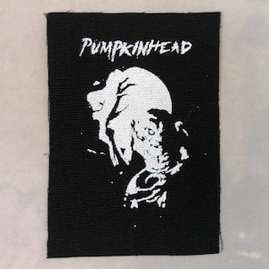 May include: Black and white embroidered patch with the text "PUMPKINHEAD" and a graphic of a creature with a moon in the background.