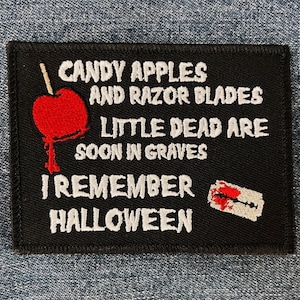 May include: Black embroidered patch with white text that reads "Candy Apples and Razor Blades Little Dead Are Soon in Graves I Remember Halloween". The patch features a red candy apple with a white stick and a white razor blade with a red drop of blood.