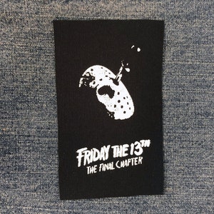 May include: Black and white iron-on patch featuring a hockey mask with a bloody knife sticking out of it. The text "FRIDAY THE 13TH" and "THE FINAL CHAPTER" is printed below the mask.