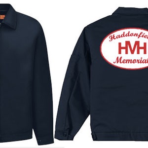 Op de afbeelding: Een donkerblauw werkjack met een rood en wit geborduurde patch op de linkerborst met de tekst "Haddonfield HM Memorial". Dezelfde patch bevindt zich op de achterkant van het jack, maar is groter en ovaalvormig.