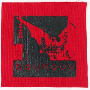 May include: Black and white iron-on patch with the word "bauhaus" in a bold font on a red background.