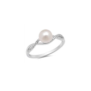 May include: A silver-toned ring featuring a lustrous, round pearl as the centerpiece. The band has a delicate, intertwined design, embellished with small, sparkling stones. The ring is set against a plain white background, highlighting its elegant simplicity.