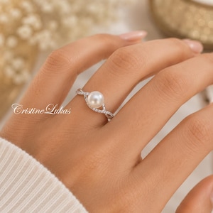 Anel de pérola natural com zircônias cúbicas e detalhe do infinito em prata de lei.