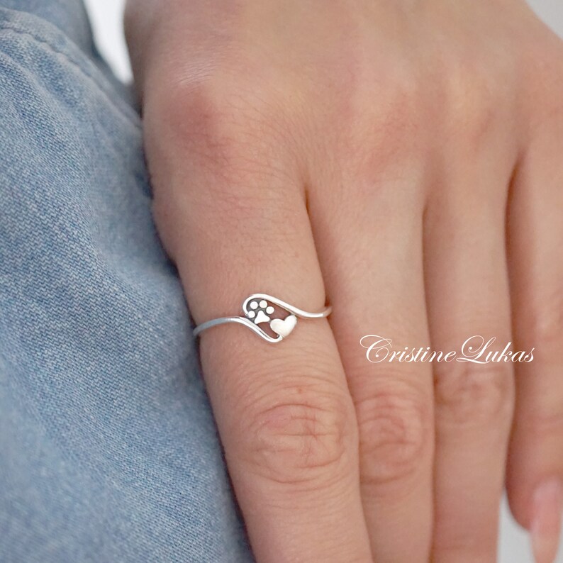 May include: A silver ring with a paw print inside a heart design.