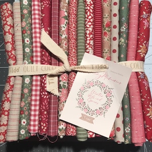 May include: A bundle of fabric strips in various red, pink, and green floral and patterned designs. The fabric is tied with a cream-colored ribbon and a tag that reads "Winter Reds and Greens" and "Tilda."