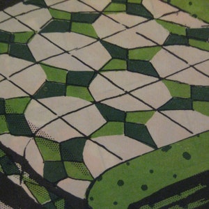 May include: A close-up of a green and white quilt with a geometric pattern. The quilt is made of squares and diamonds, and the fabric is textured.