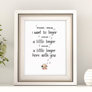 Pode incluir: Uma impressão emoldurada com o texto "I want to linger a little longer here with you." A impressão está em uma moldura branca, e a imagem inclui um vaso de flores e uma esfera branca decorativa.