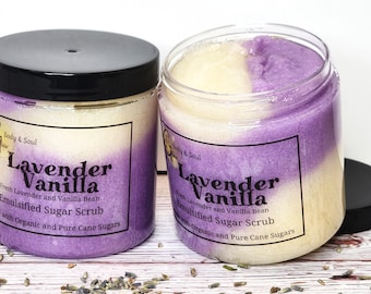Op de afbeelding: Twee doorzichtige potten met geëmulgeerde suikerscrub met zwarte deksels. De potten zijn gelabeld met "Lavender Vanilla" met tekst die verse lavendel- en vanillebonen ingrediënten aangeeft. De scrub is een mix van paarse en crèmekleuren.