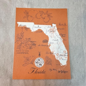 May include: An orange-colored vintage postcard featuring a map of Florida with illustrations of oranges, a bird, and a fish. The map highlights cities like Miami, Orlando, and Jacksonville. Text includes "Florida" and "In God We Trust."