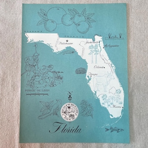 May include: A teal-colored vintage map of Florida, featuring illustrations of oranges, a bird, and the state seal. The map includes the names of cities like Tallahassee, Jacksonville, and Miami. The text "Florida" is written in cursive.