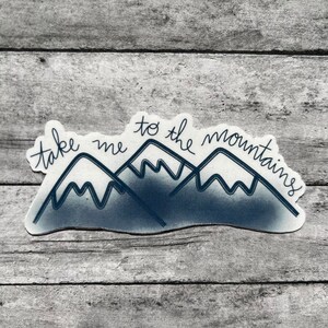 May include: A sticker with a blue mountain range and the text "take me to the mountains".