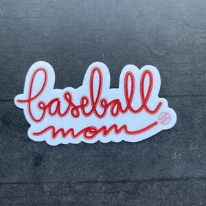 May include: White sticker with red cursive text that says "baseball mom" with a small red baseball graphic.