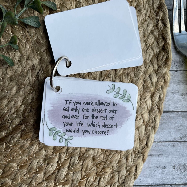May include: A set of conversation starter cards with a purple watercolor background and green leaves. The card shown reads "If you were allowed to eat only one dessert over and over for the rest of your life, which dessert would you choose?"
