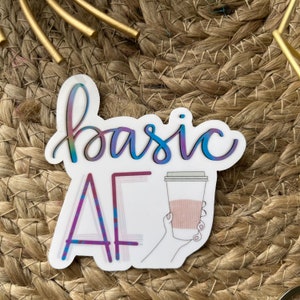 May include: A white sticker with the text "basic af" in a rainbow gradient. The "a" in "af" is a stylized letter with a purple and blue gradient. A hand holding a coffee cup with a pink and brown gradient is to the right of the text.