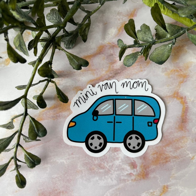 May include: A blue minivan sticker with the text "mini van mom" in white cursive writing.